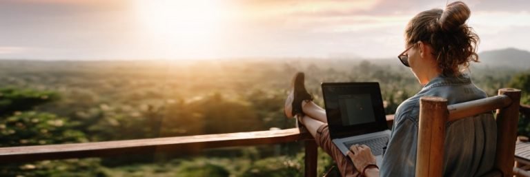 Woman with laptop on desk overlooking the sunset