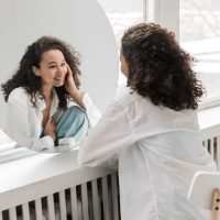 Woman in a white shirt looking in a mirror